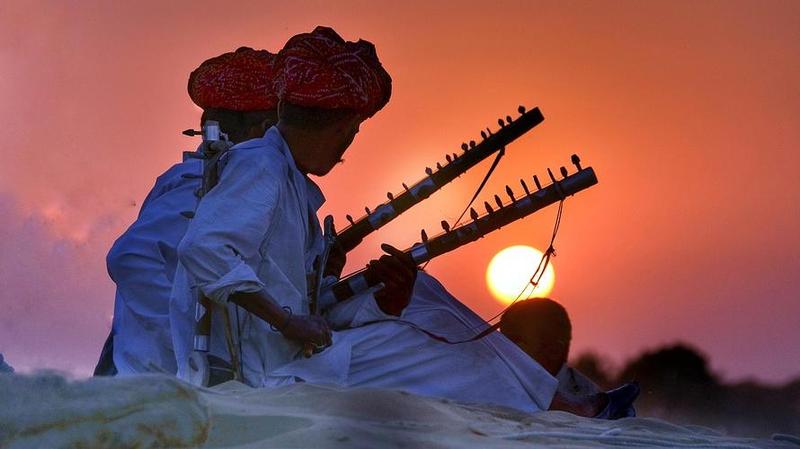 indian man in the dessert playing the sitar