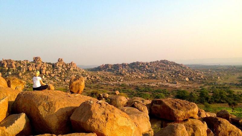 Woman meditating in the rocky scernery of Hampi, India