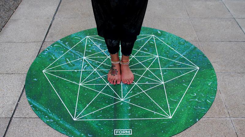 feet standing on a round yoga mat that looks like one of the chakra symbols