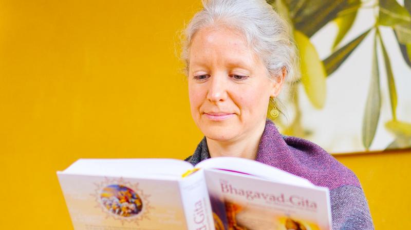Frau liest aus der Bhagavad Gita